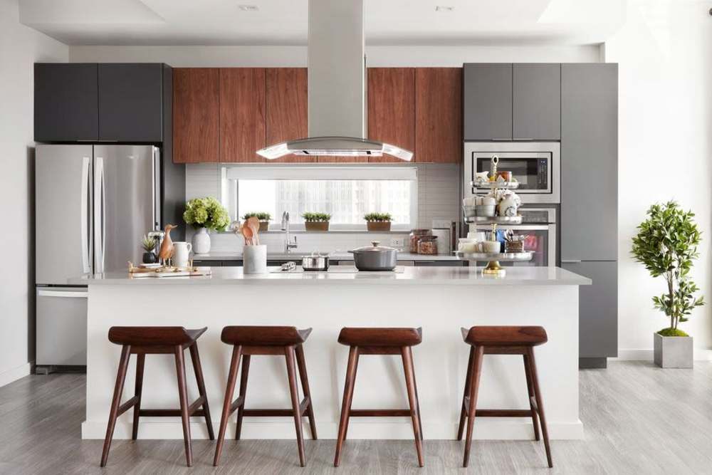 Open kitchen with bar counter, waterfall sink, stove, microwave and granite countertops at Ardan in Dallas, Texas
