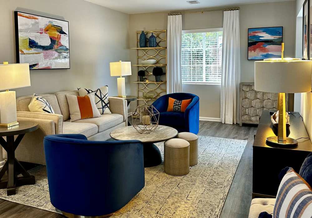 Open layout living room with hard-wood style flooring, a couch, coffee table, and chairs at Battleground North in Greensboro, North Carolina