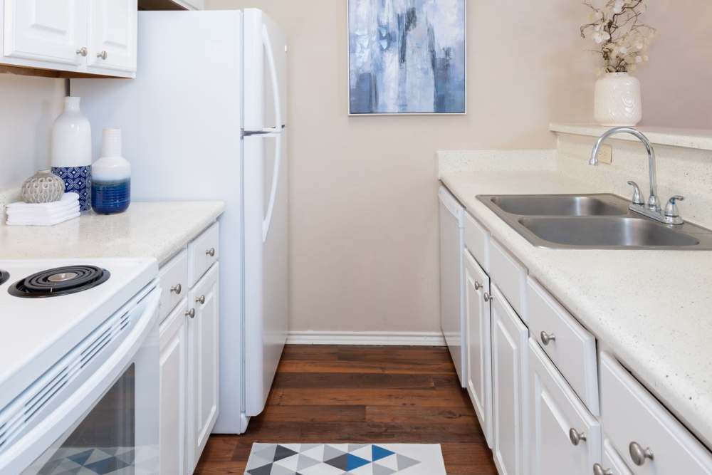 Modern kitchen with sleek white cabinetry and polished countertops at Charter Oak in Euless, Texas.