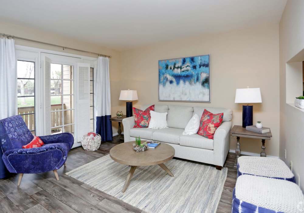 Spacious living room with wood-style flooring and large window at Wasatch Club Apartments in Midvale, Utah,