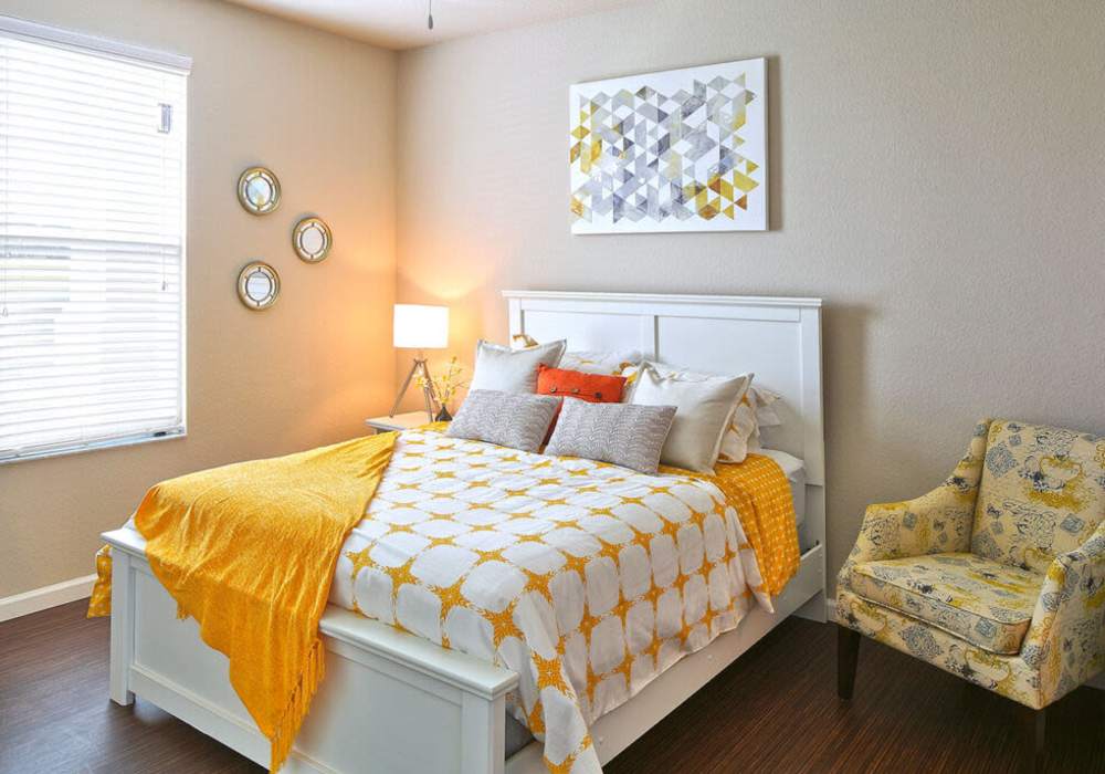 Bright bedroom with yellow accents and modern decor at Messina Luxury Apartments in New Smyrna Beach, Florida