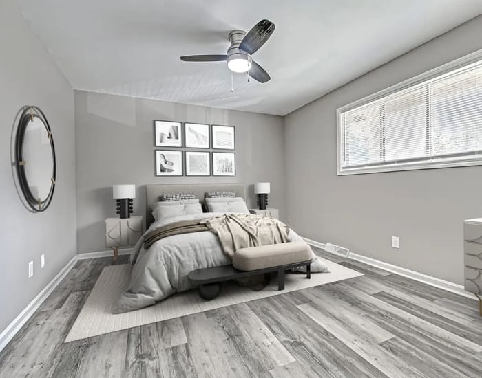 Apartment bedroom with a comfortable bed, mirror and a large window at Woodside Village in Valparaiso, Indiana