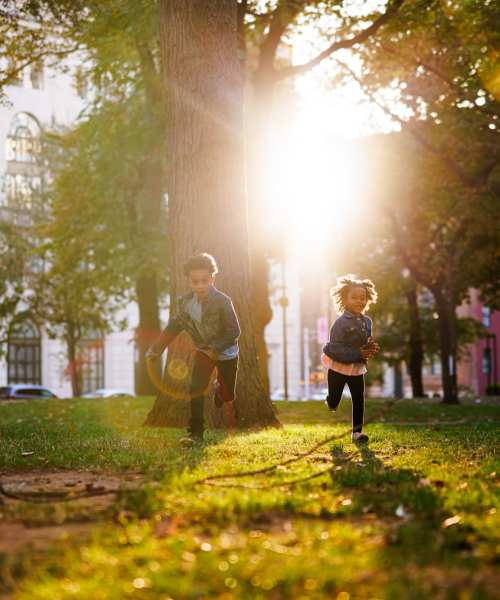 Kids enjoying a sunny outdoor lawn with greenery and walking paths at Granada Gardens Apartments in Warrensville Heights, Ohio