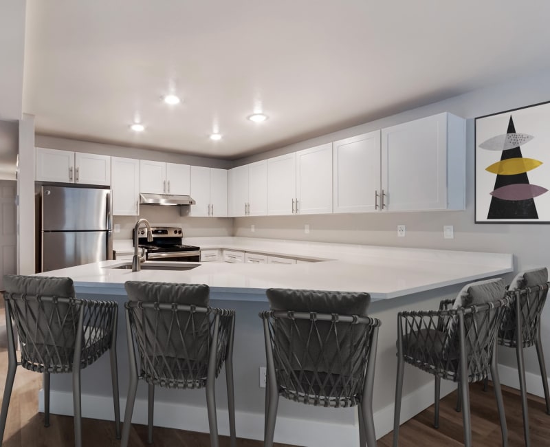 Modern kitchen with stainless steel appliances and counter seating in a model home at Chandlers Bay Apartments in Kent, Washington