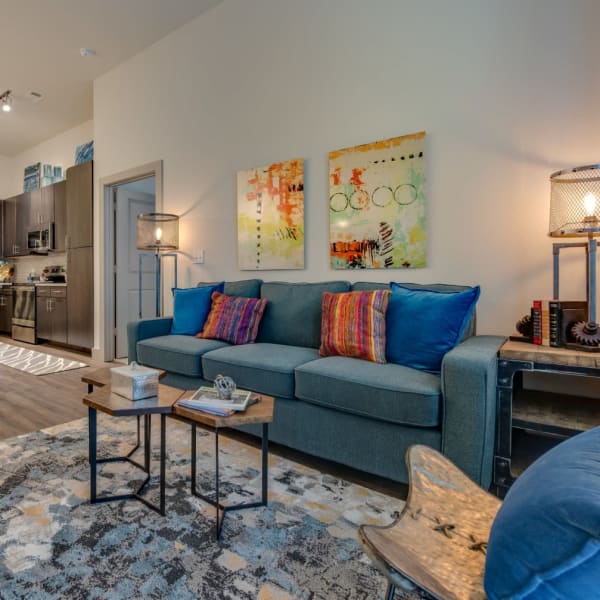 Open concept apartment living room with sofa, coffee table, and area rug at Bellrock Upper North in Haltom City, Texas