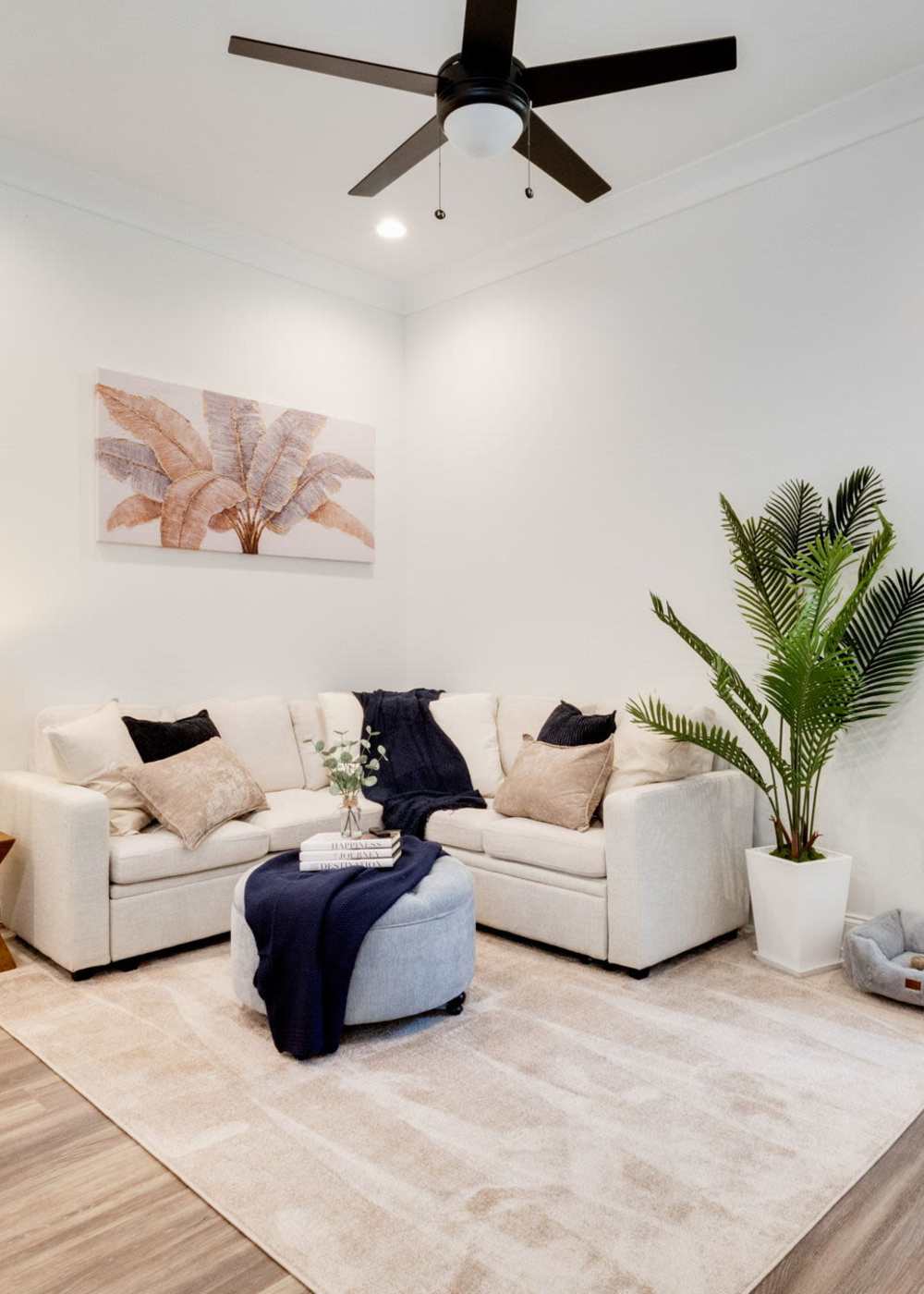 Spacious living room with wood-style flooring and a fancy ceiling fan at Trinity Villas in Lafayette, Louisiana