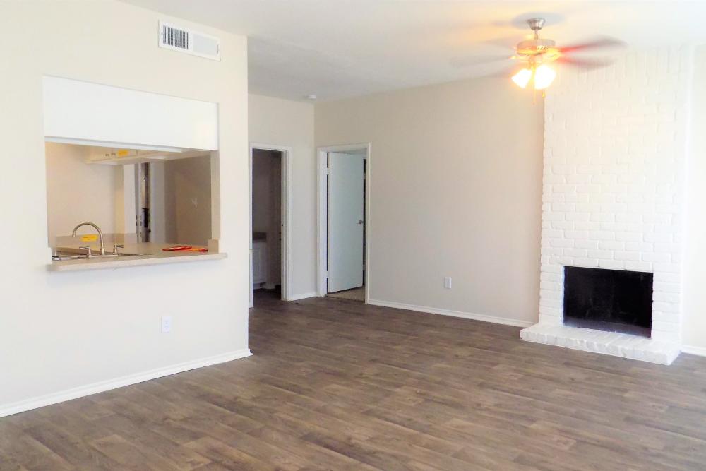 Spacious and well-lit apartment living area with fireplace and lighted ceiling fan at Branch Creek Apartments in Carrollton, Texas