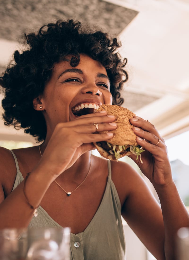 Resident enjoying a hamburger with a friend near Marquis at The Cascades in Tyler, Texas