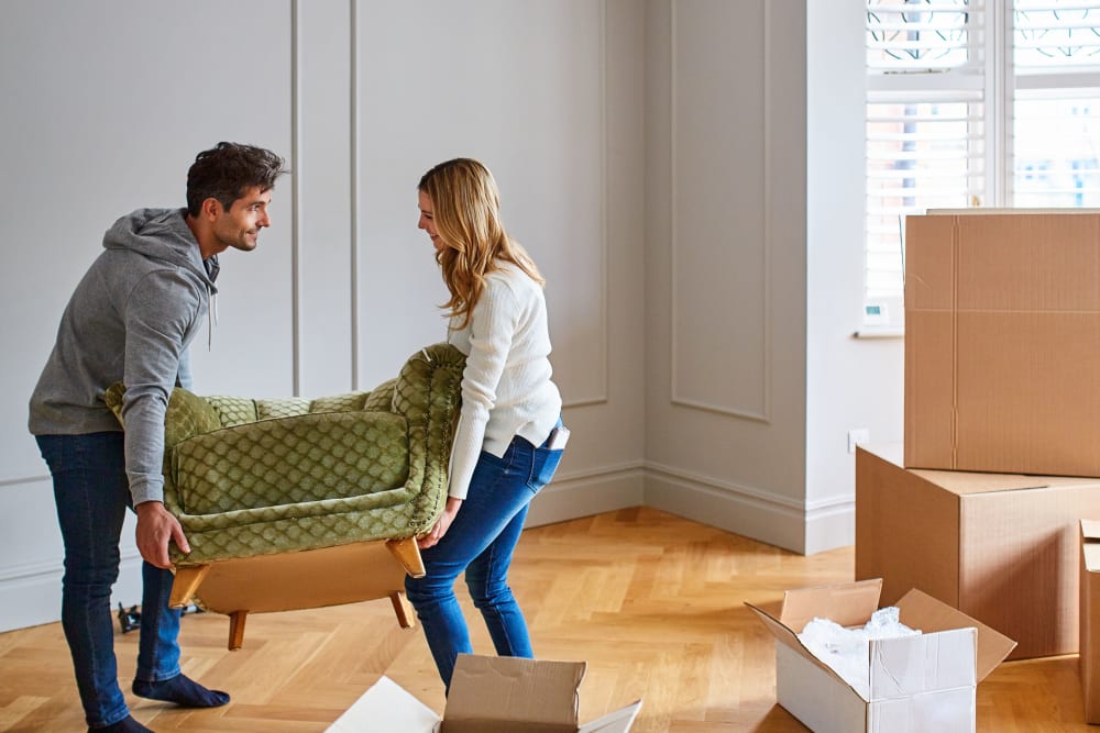 A couple arranging furniture at their new apartment near Trojan Storage of Salinas Blanco in Salinas, California