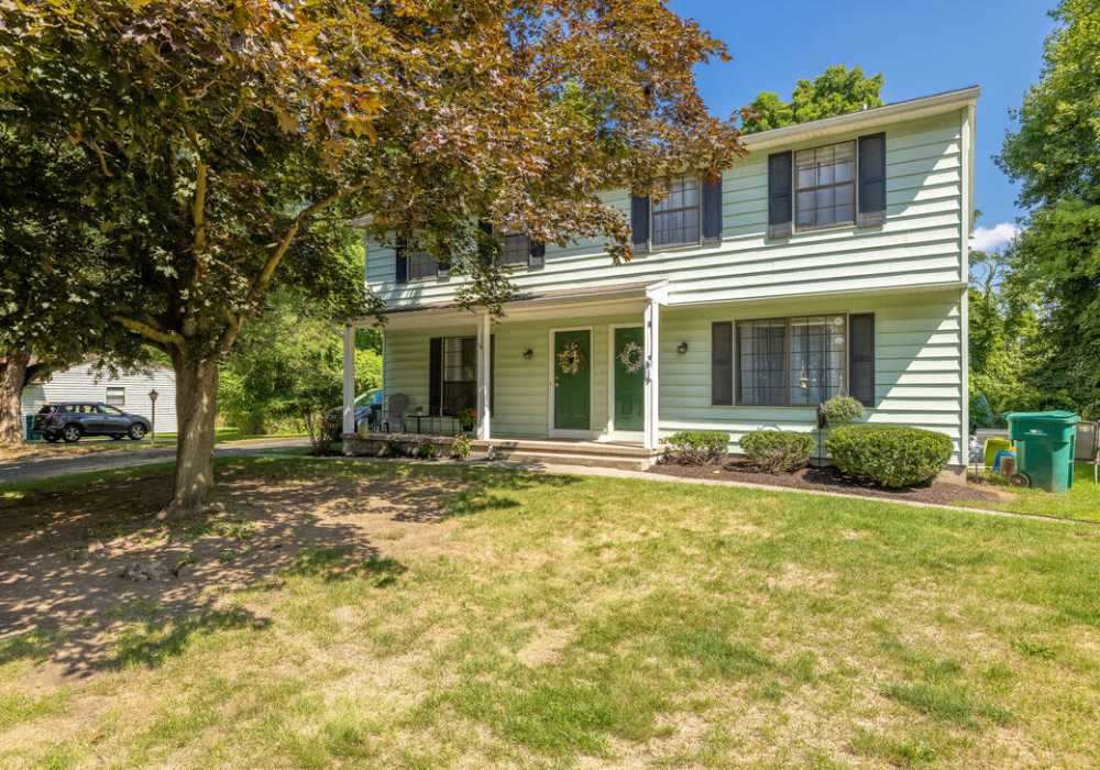Charming home with lush greenery and porch at Jefferson Manor Townhomes in Fairport, New York