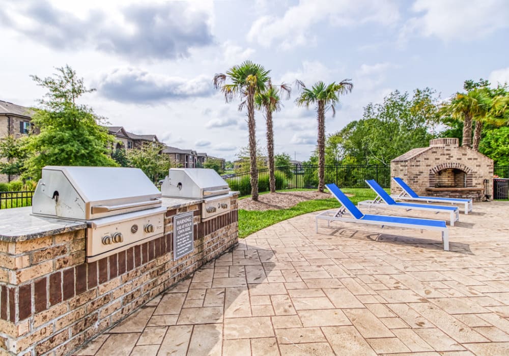 High-end, shared stainless-steel barbecue grills, grass area, chaise lounge chairs and fireplace at Glass Creek in Mt Juliet, Tennessee