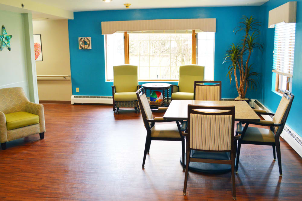 Cheerful sitting area with tables and yellow chairs at Wyndemere Memory Care in Green Bay, Wisconsin. 