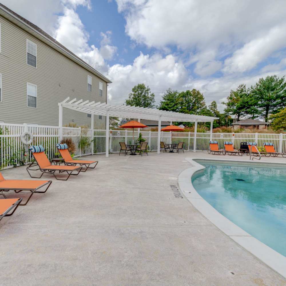 Charming outdoor lounge area with vibrant orange seating and a sparkling pool at Boulder Springs in Maryland Heights, Missouri.