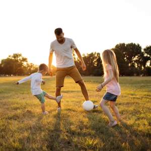 Resident man playing soccer with his children near The Kensley in Spanish Fort, Alabama 