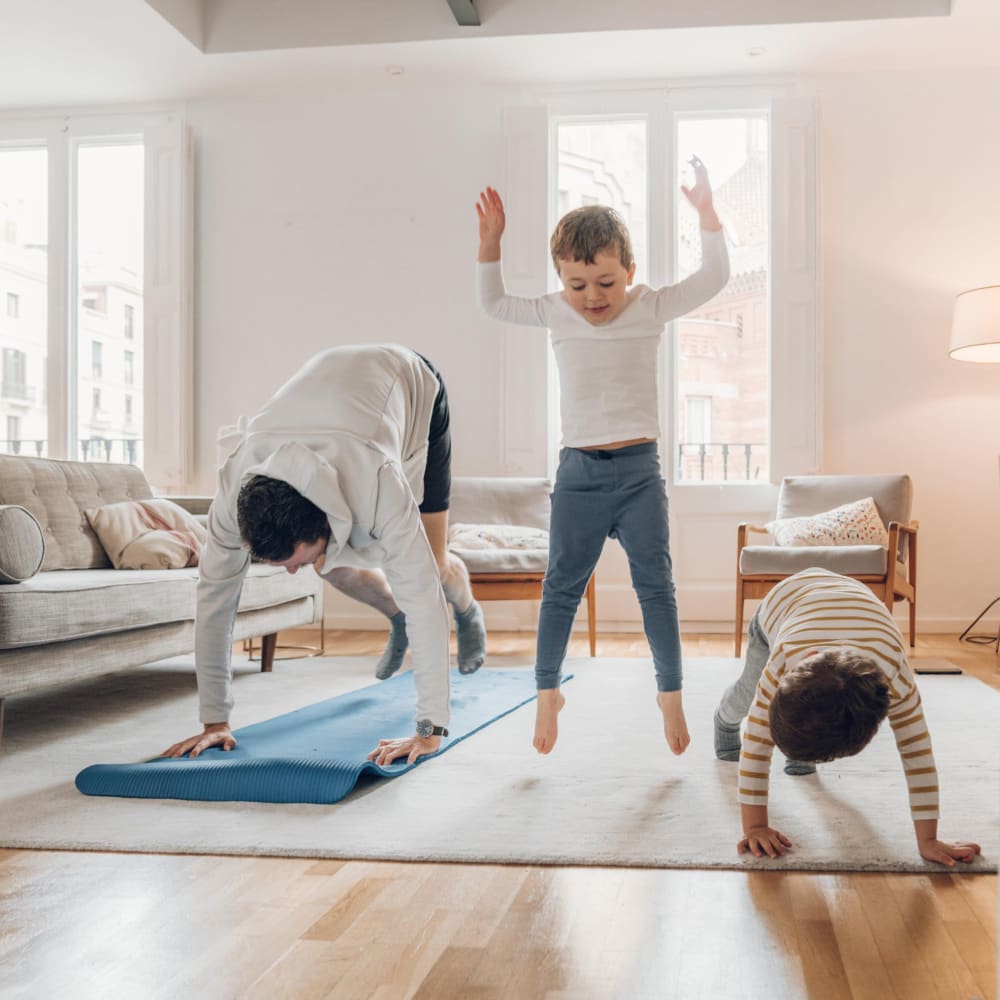 Family doing yoga together in their living room at Mandalane Apartments in Wheeling, Illinois