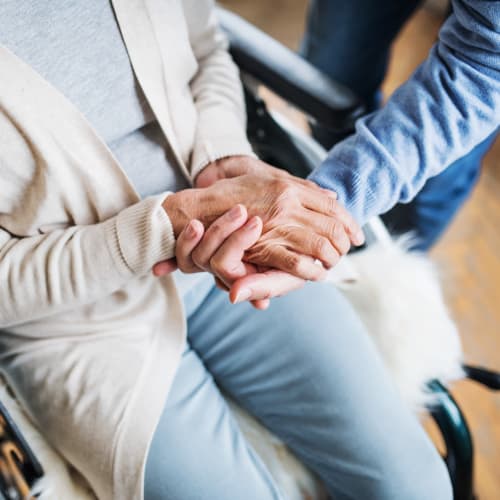 Resident holding hands with a caretaker at Oxford Springs Tulsa Memory Care in Tulsa, Oklahoma