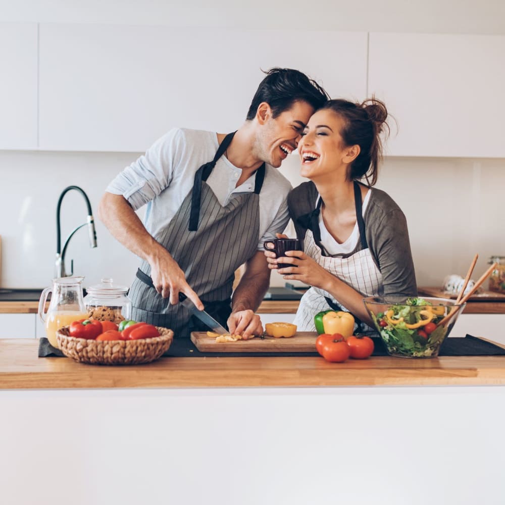 Happy couple cooking at Royal I and II Apartments in Los Angeles, California