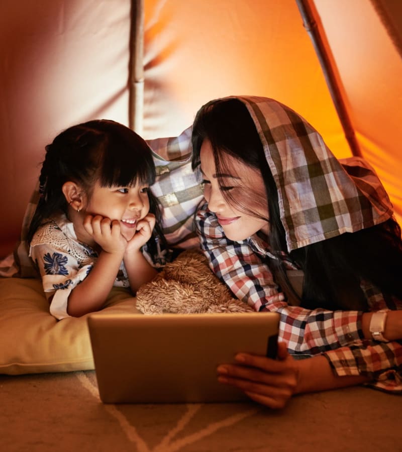 Mother and daughter watching a movie on a tablet inside a cozy tent in their home at James River Pointe in Richmond, Virginia