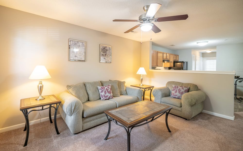 Living room with a ceiling fan and wall-to-wall carpeting at The Village at Brierfield Apartment Homes in Charlotte, North Carolina
