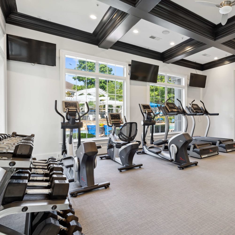 Well-equipped fitness center with TVs and views of the pool at Five Oaks in Tucker, Georgia