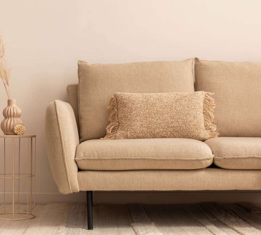 Beige sofa with decorative pillow and vase at Avia Lofts at Maple Road in Amherst, New York