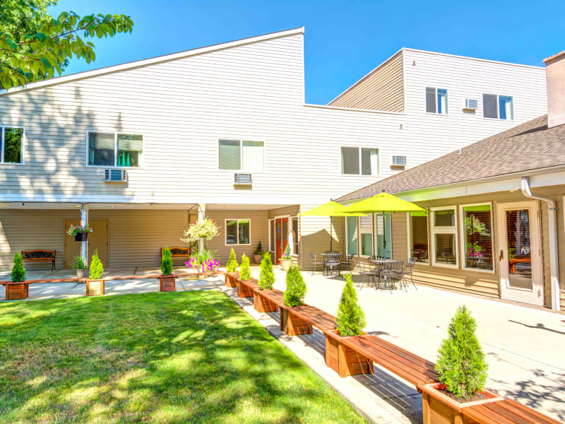 Patio with tables and umbrellas and bench seating at Junction City Retirement and Assisted Living in Junction City, Oregon. 