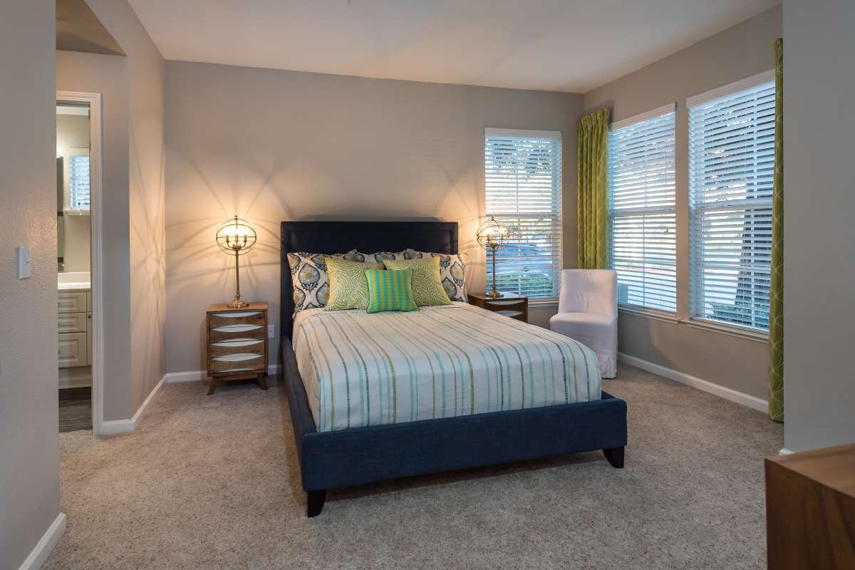 Master bedroom with attached bathroom and carpet flooring at Nantucket Apartments in Santa Clara, California
