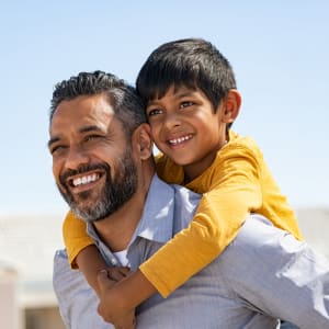 Smiling resident carrying his son on his back at Highlands of Duncanville in Duncanville, Texas