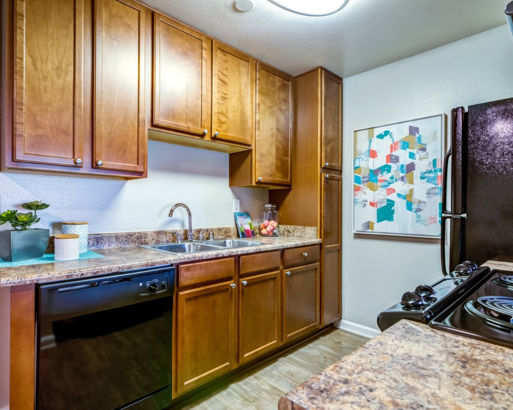 Modern kitchen with ample cupboard space and granite countertops in a model home at Sofi Poway in Poway, California