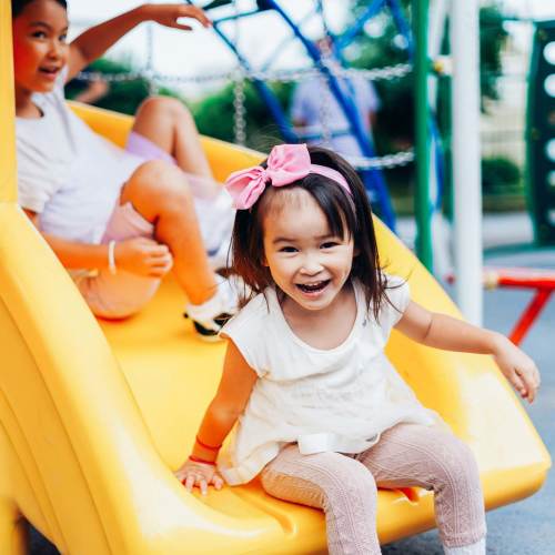 Charming play area with vibrant yellow slide at Del Norte Duplexes in Yukon, Oklahoma.