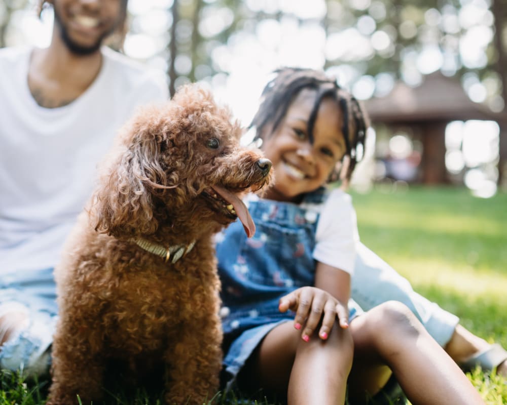 Resident father and daughter spending time outside with their dog in a park near Castlegate Collier Hills in Atlanta, Georgia