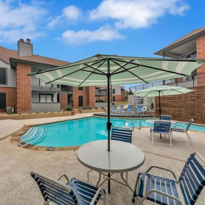 Pool and patio tables and umbrellas at a Monticello Asset Management community in Dallas, Texas