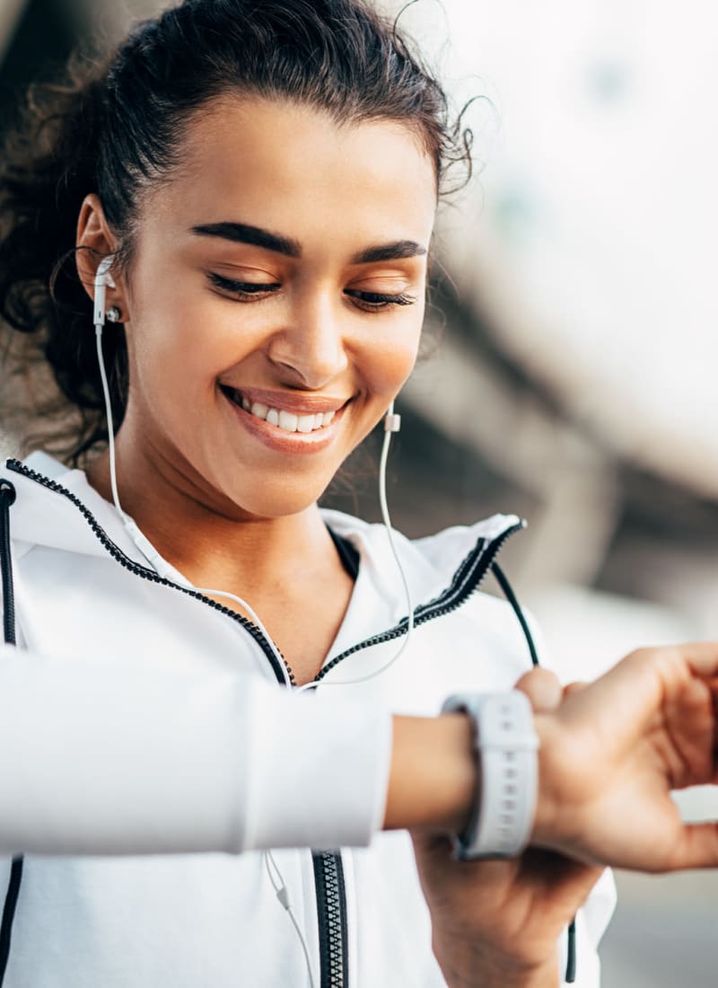 Young woman setting her smart watch while exercising near Marquis at Carmel Commons in Charlotte, North Carolina