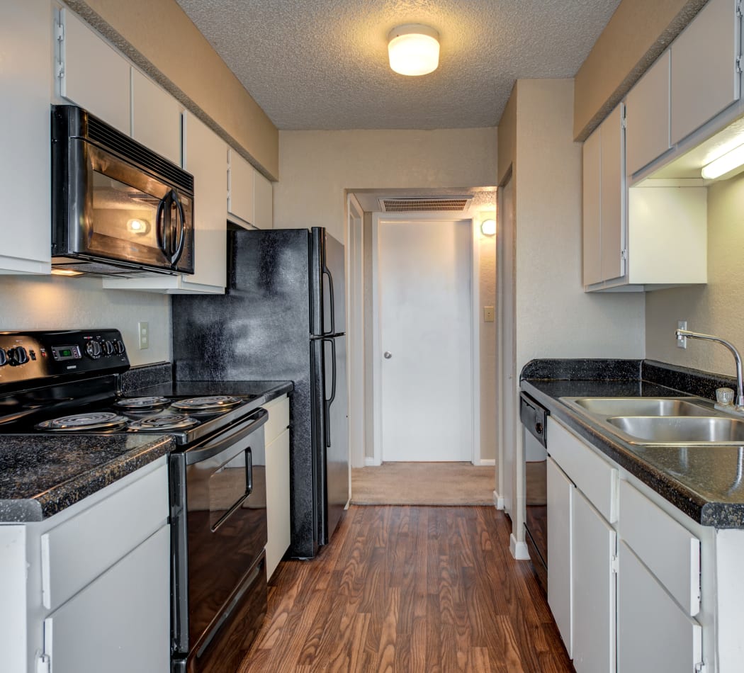 Black appliances and hardwood floors in model home's kitchen at The Belmont in Grand Prairie, Texas