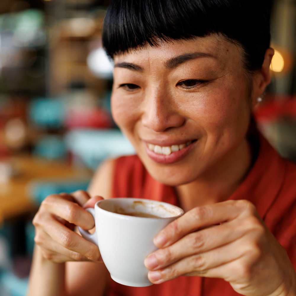 Resident holding a white coffee cup at Atrium Gardens in Arlington, Texas