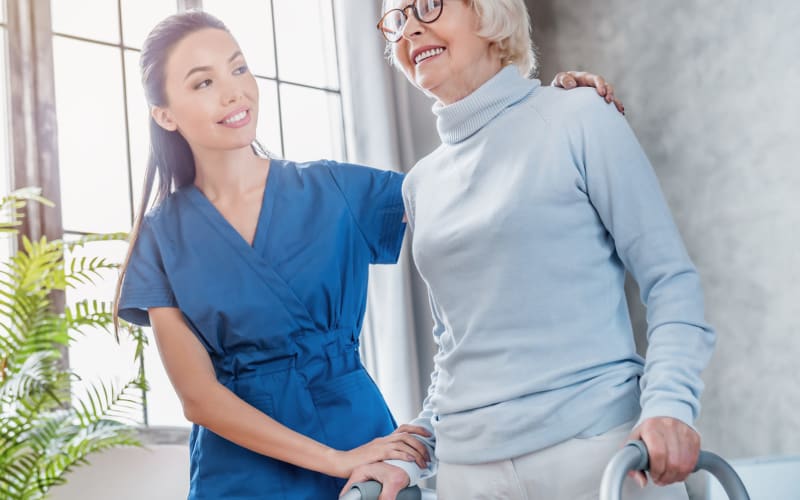 caregiver assisting a resident with a walker to her feet at Blossom Springs in Oakland Twp, Michigan