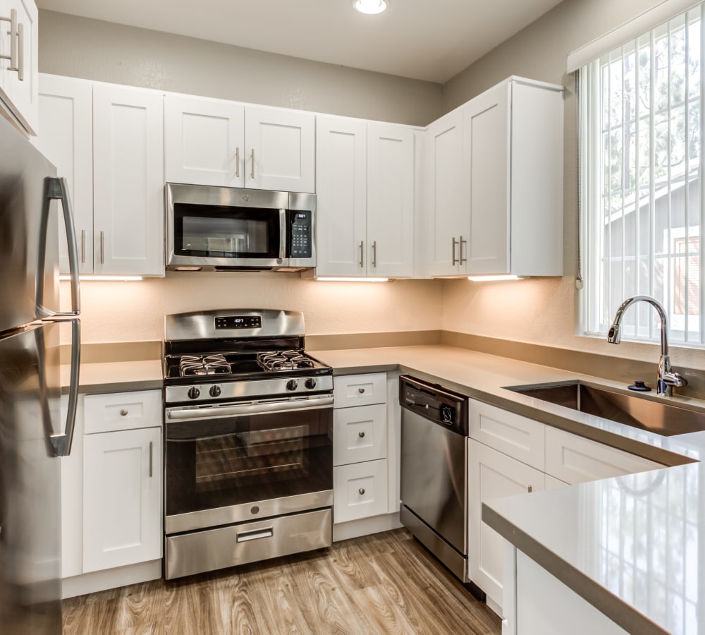 Modern kitchen with hardwood floors and stainless-steel appliances in a model home at Sofi Highlands in San Diego, California