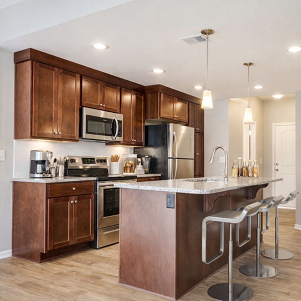 Modern kitchen with stainless-steel appliances, island countertop and barstool at Chapel Ridge in Lees Summit, Missouri