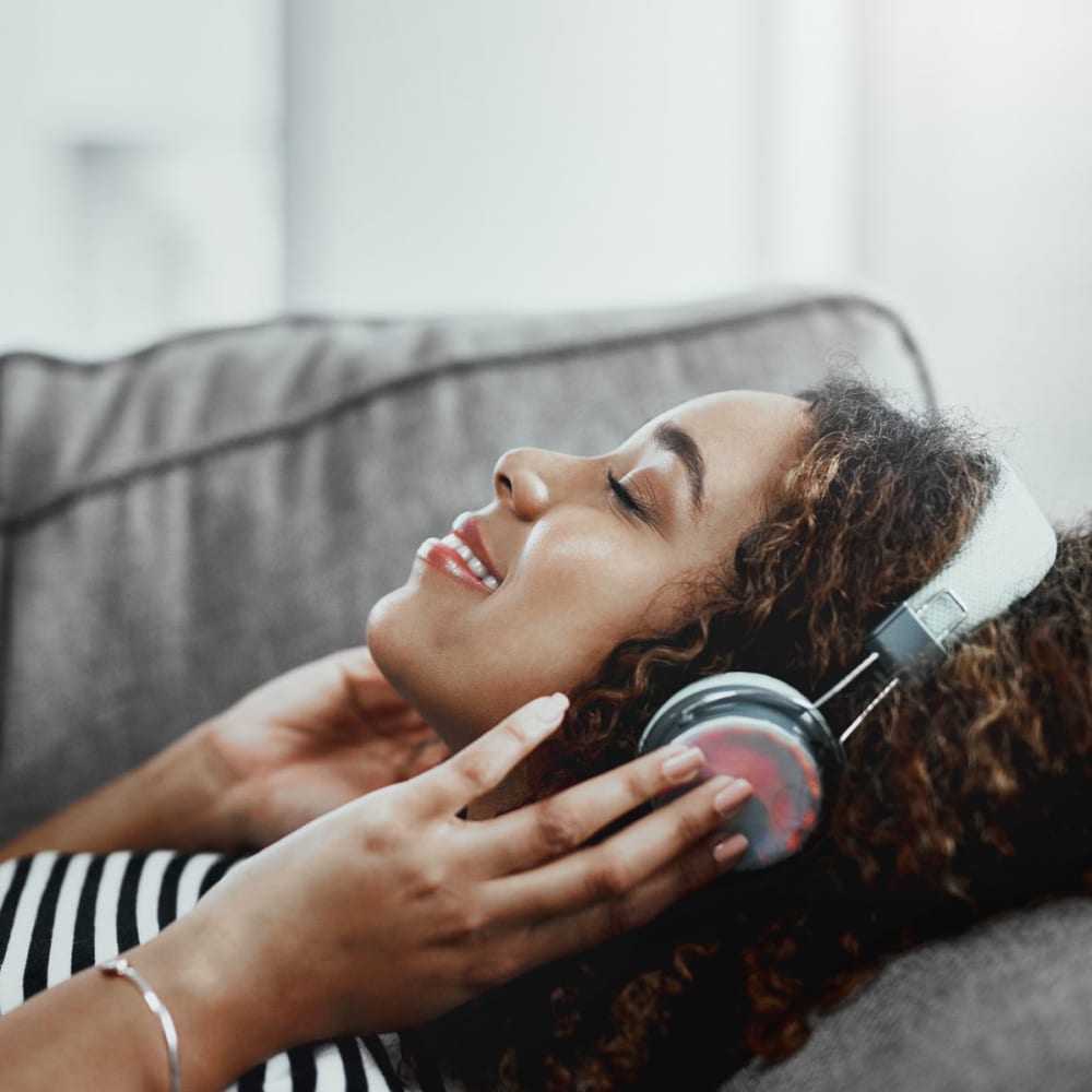 Resident relaxing on the couch and listening to music on headphones in her home at Oaks Hiawatha Station in Minneapolis, Minnesota