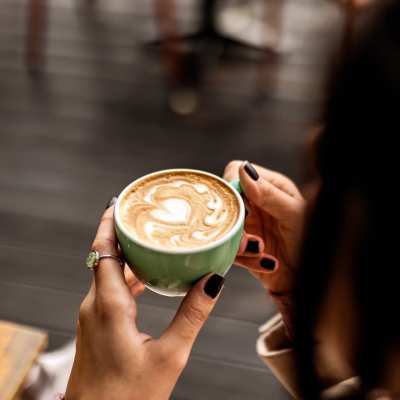 Woman having coffee at a cafe nearby UTE Creek Apartments in Longmont, Colorado