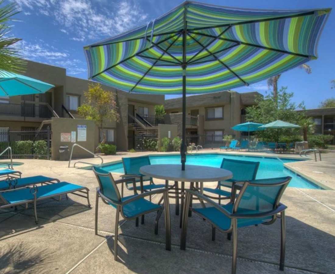 Laid back chairs with shade near the swimming pool at Raystone Apartments in Phoenix, Arizona