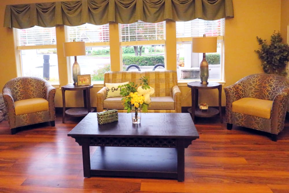 A seating area with hardwood floors and large window at Meadowlark Senior Living in Lebanon, Oregon.