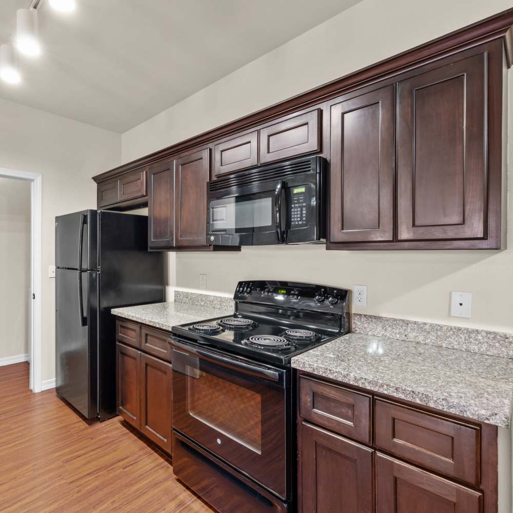 Wooden cabinets and black appliances in the kitchen at Las Torres Apartments in El Paso, Texas