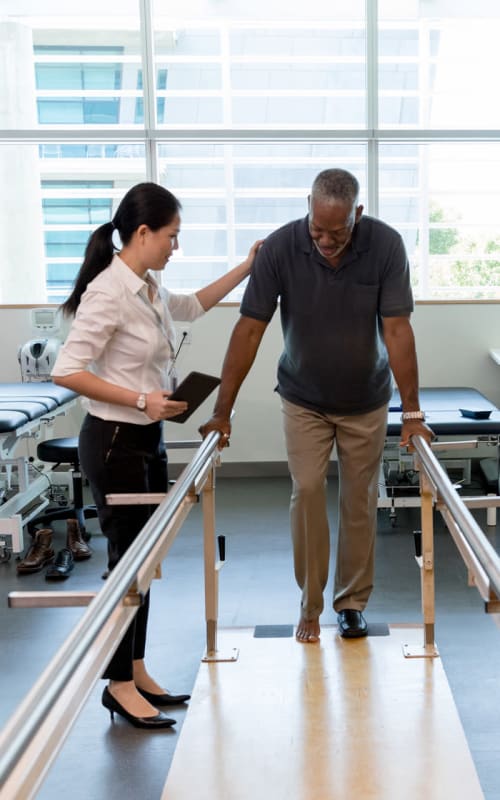 Resident working with a caretaker in a gym at a Jaybird Senior Living community