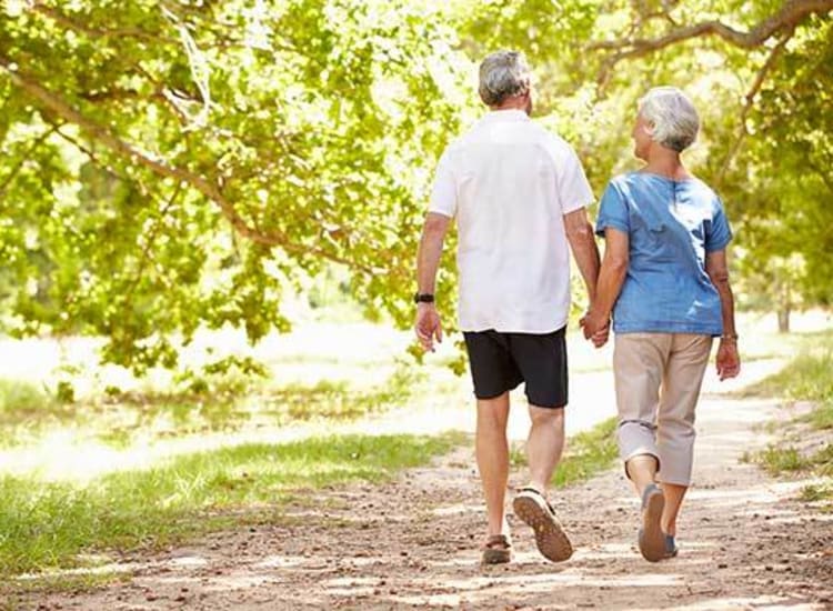 Couple taking a stroll through the verdant grounds at Arcadia Senior Living Pace in Pace, Florida