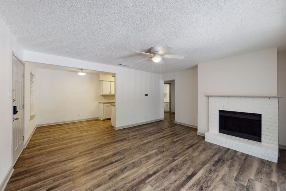 Spacious living room with a fireplace and wood-style flooring at The Haylie in Garland, Texas