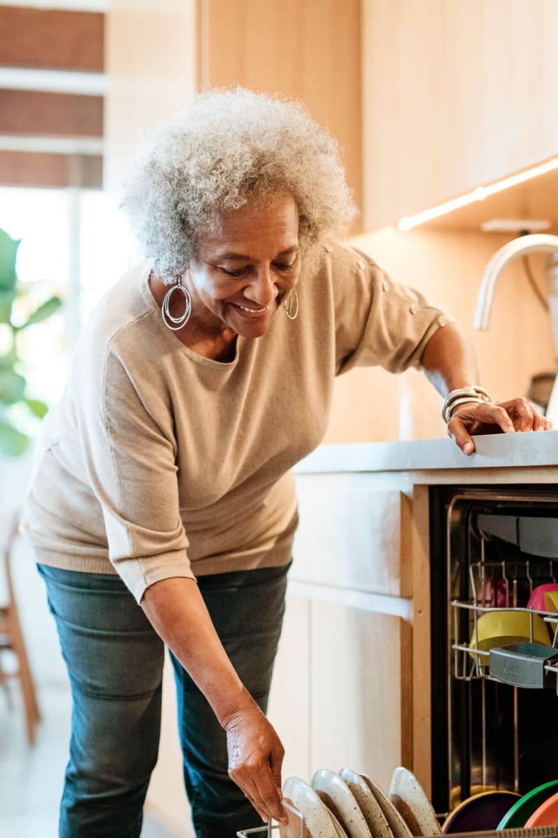 Resident emptying the dishwasher in their home at Transitions At Home in Elkhorn, Wisconsin