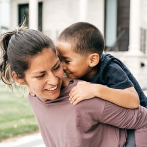 Resident with child on back smiling at Dove Hollow Apartments in Allen, Texas