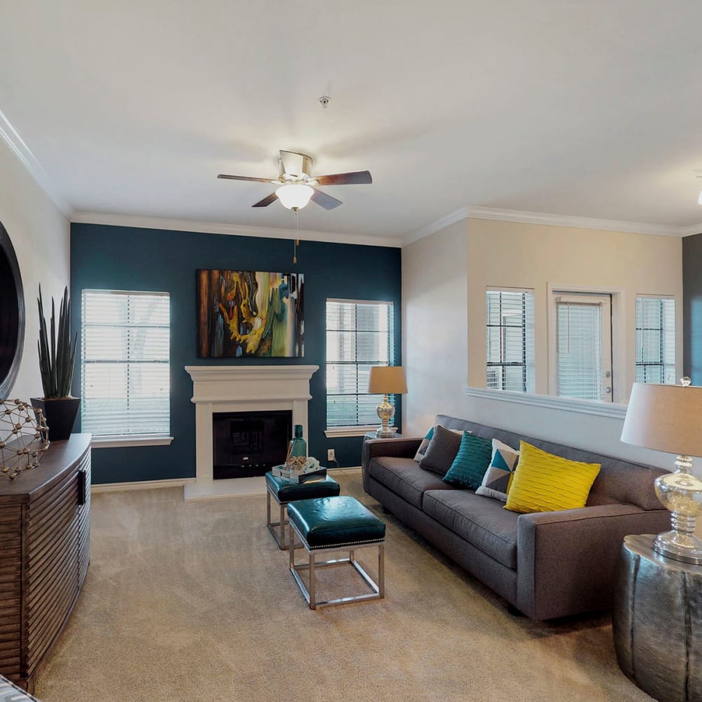 Plush carpeting and a fireplace in a model home's living area at Oaks Riverchase in Coppell, Texas