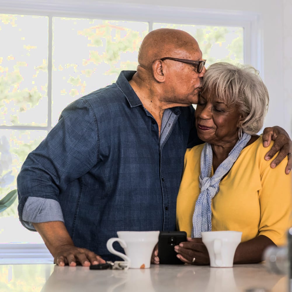 A man kissing his wife on the forehead at a Ridgeline Management Company senior living property